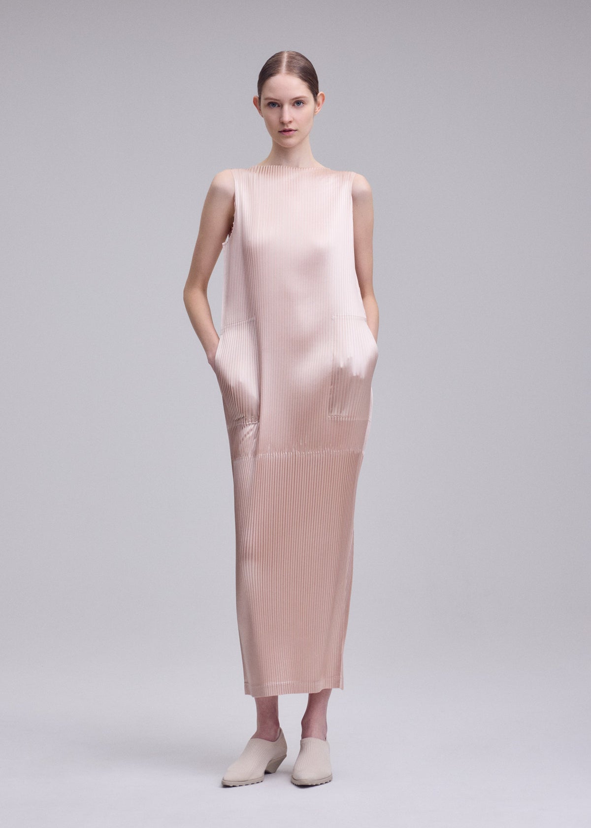 A model wears the ISSEY MIYAKE GLOSSED PANELS PLEATS glossed-panels-pleats-dress-grey.