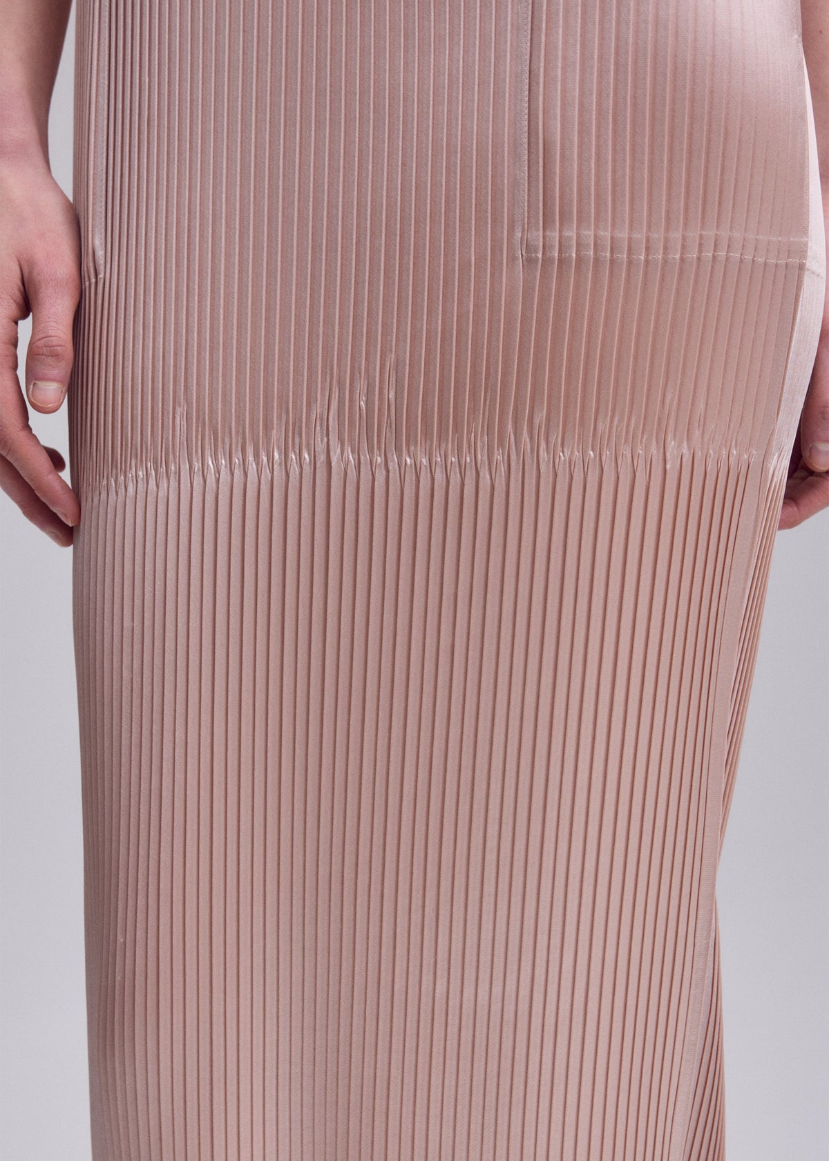 A model wears the ISSEY MIYAKE GLOSSED PANELS PLEATS glossed-panels-pleats-dress-light-pink.