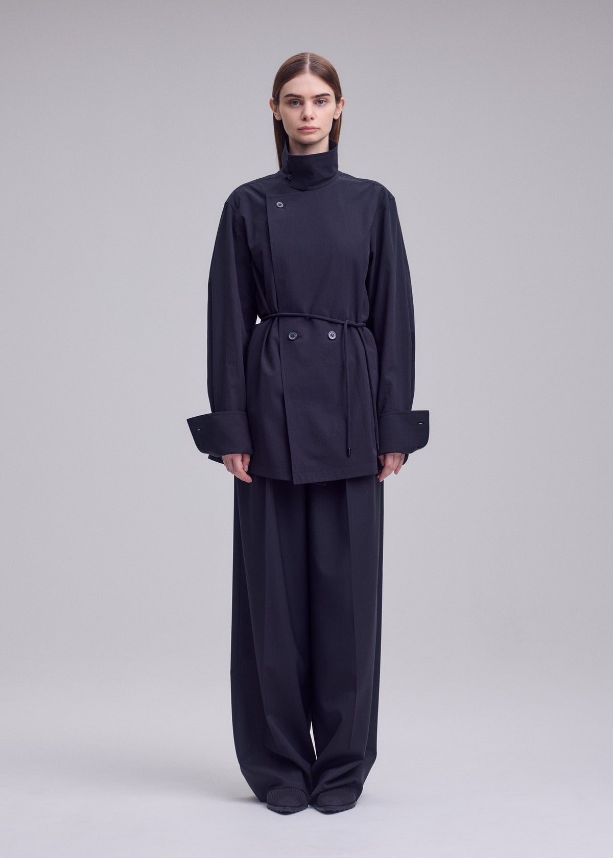 A model wears the ISSEY MIYAKE MONSIEUR SHIRT monsieur-shirt-bolo-tie-belt-shirt-white.
