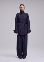 A model wears the ISSEY MIYAKE MONSIEUR SHIRT monsieur-shirt-bolo-tie-belt-shirt-white.