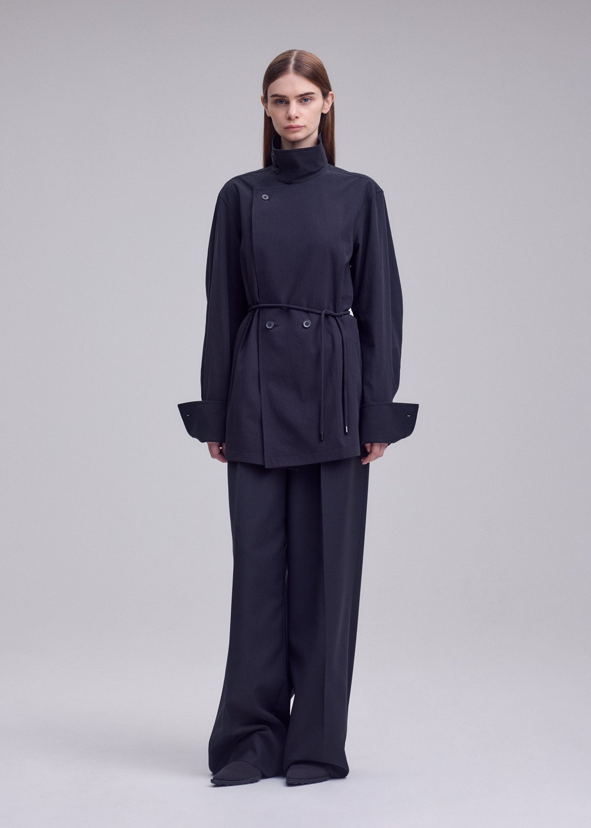 A model wears the ISSEY MIYAKE MONSIEUR SHIRT monsieur-shirt-bolo-tie-belt-shirt-white.