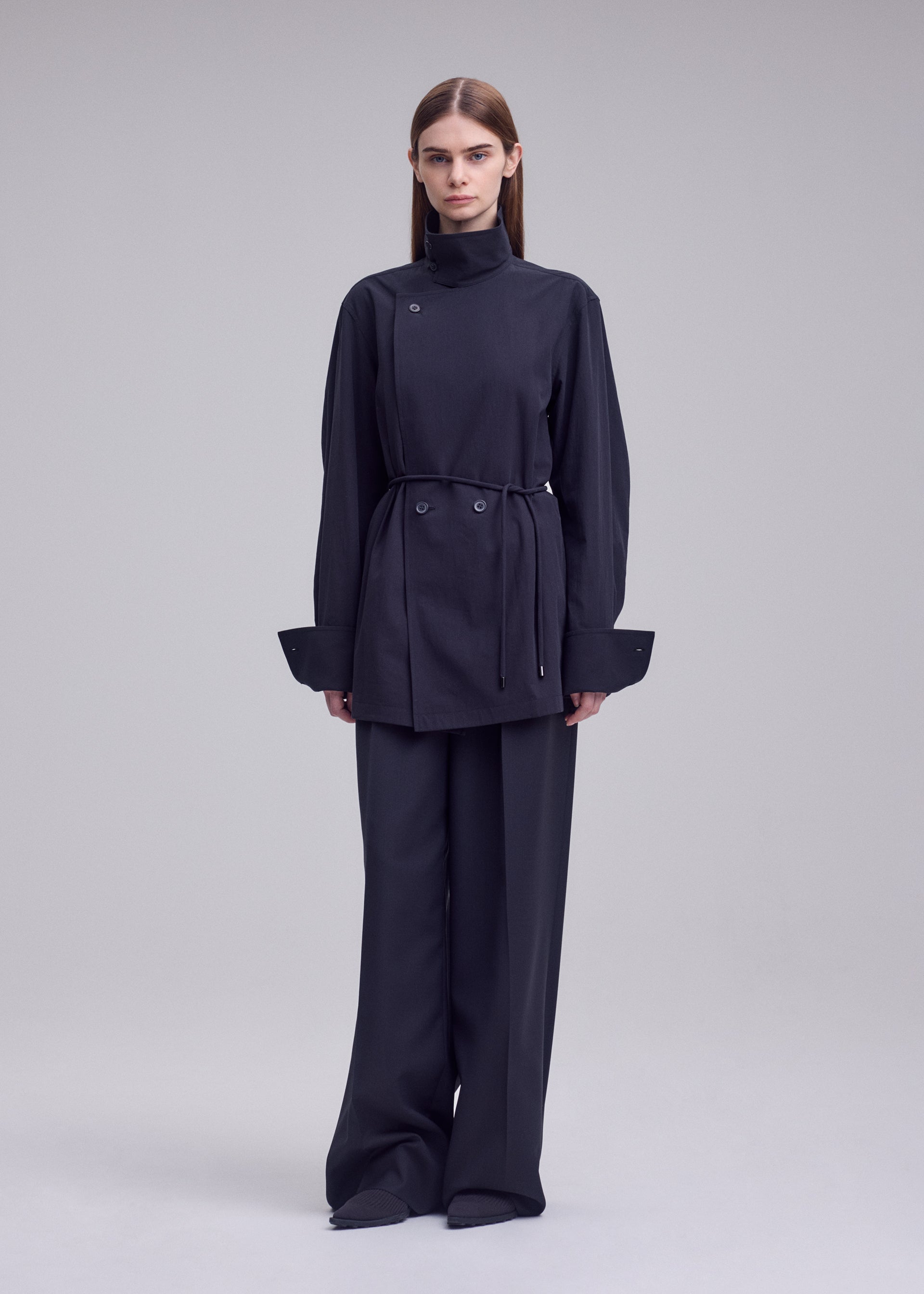 A model wears the ISSEY MIYAKE MONSIEUR SHIRT monsieur-shirt-bolo-tie-belt-shirt-white.