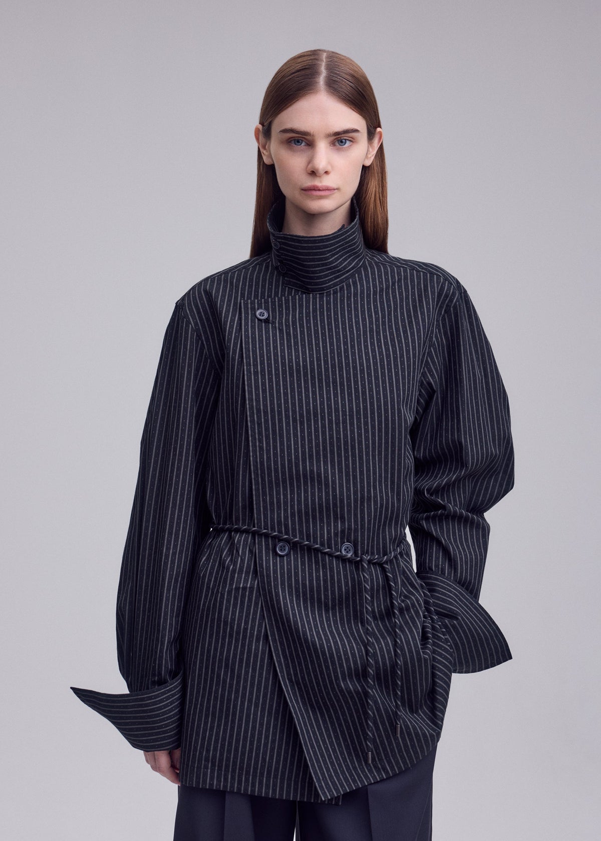 A model wears the ISSEY MIYAKE MONSIEUR SHIRT(DOBBY STRIPE) monsieur-shirt-dobby-stripe-bolo-tie-belt-shirt-white-hued.