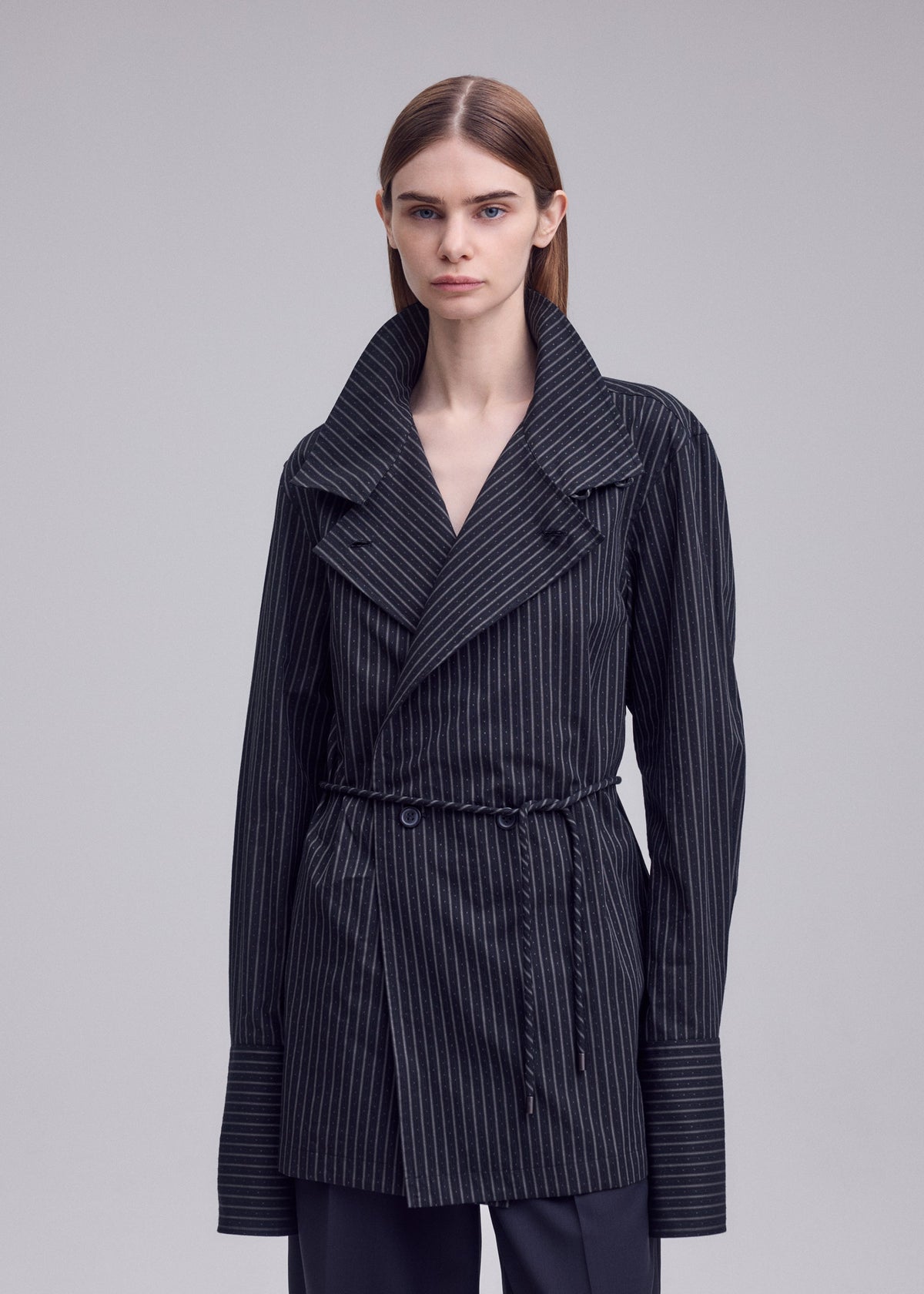 A model wears the ISSEY MIYAKE MONSIEUR SHIRT(DOBBY STRIPE) monsieur-shirt-dobby-stripe-bolo-tie-belt-shirt-black-hued.