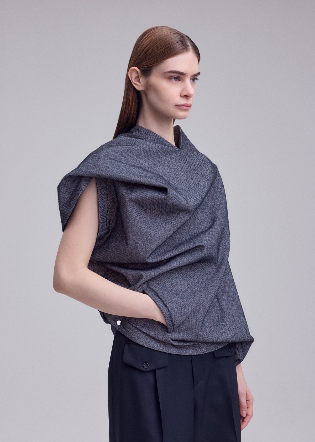 A model wears the ISSEY MIYAKE REFLECTION reflection-top-grey.