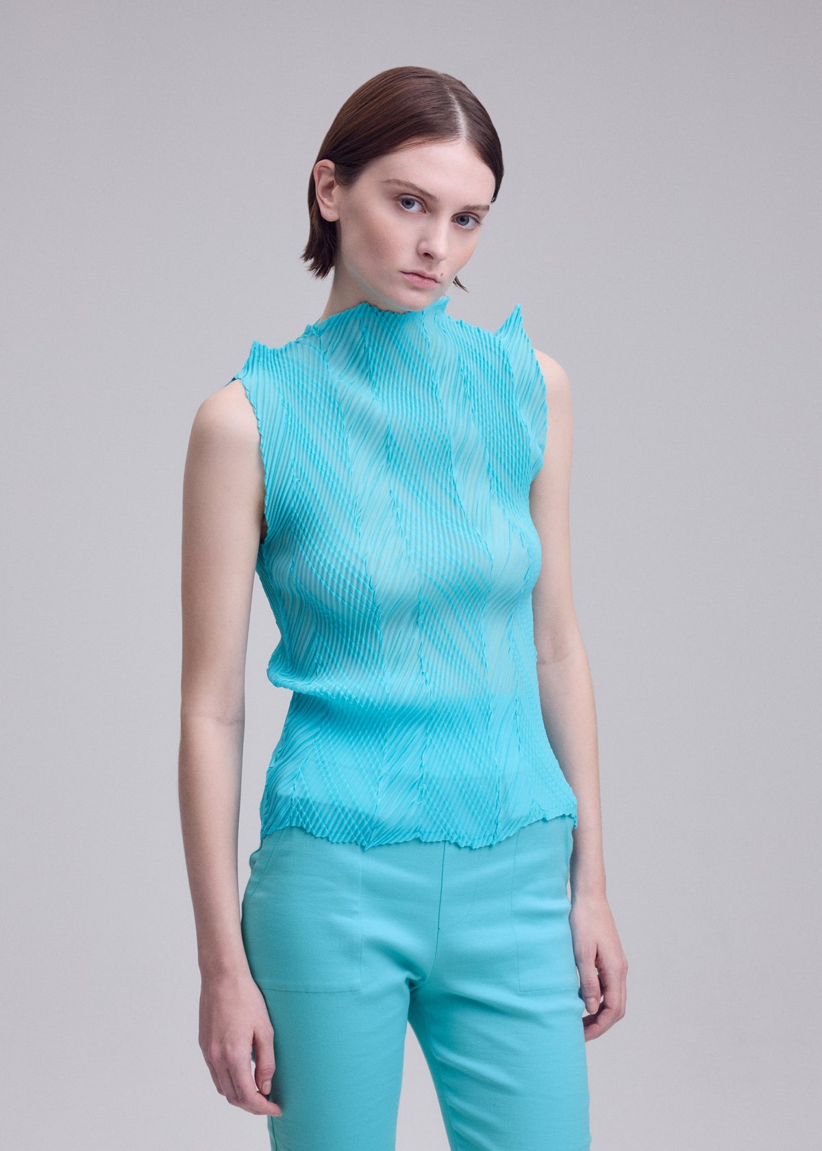 A model wears the ISSEY MIYAKE ZIGZAG PLEATS zigzag-pleats-top-dull-cream.