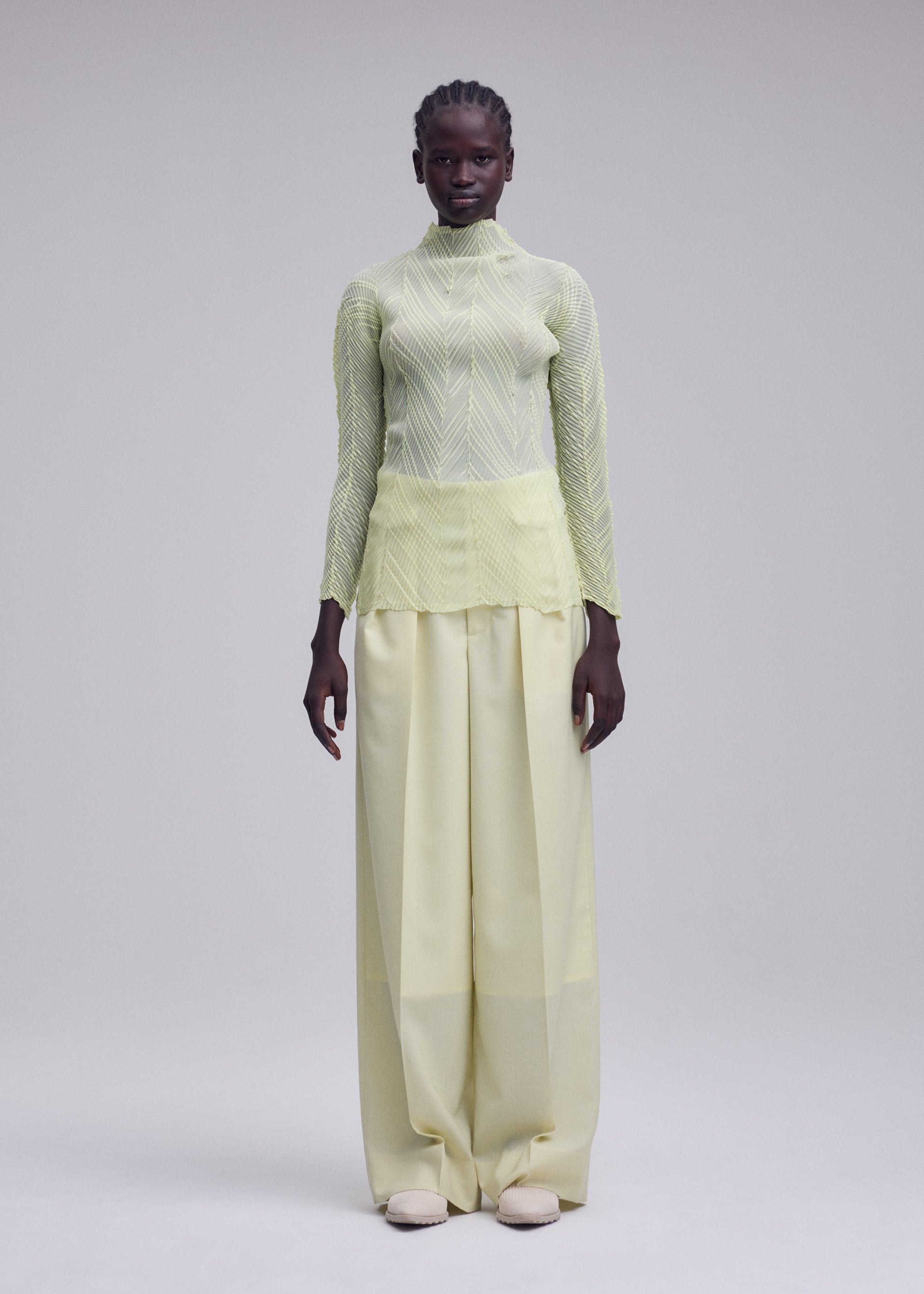 A model wears the ISSEY MIYAKE ZIGZAG PLEATS zigzag-pleats-long-sleeved-top-black.
