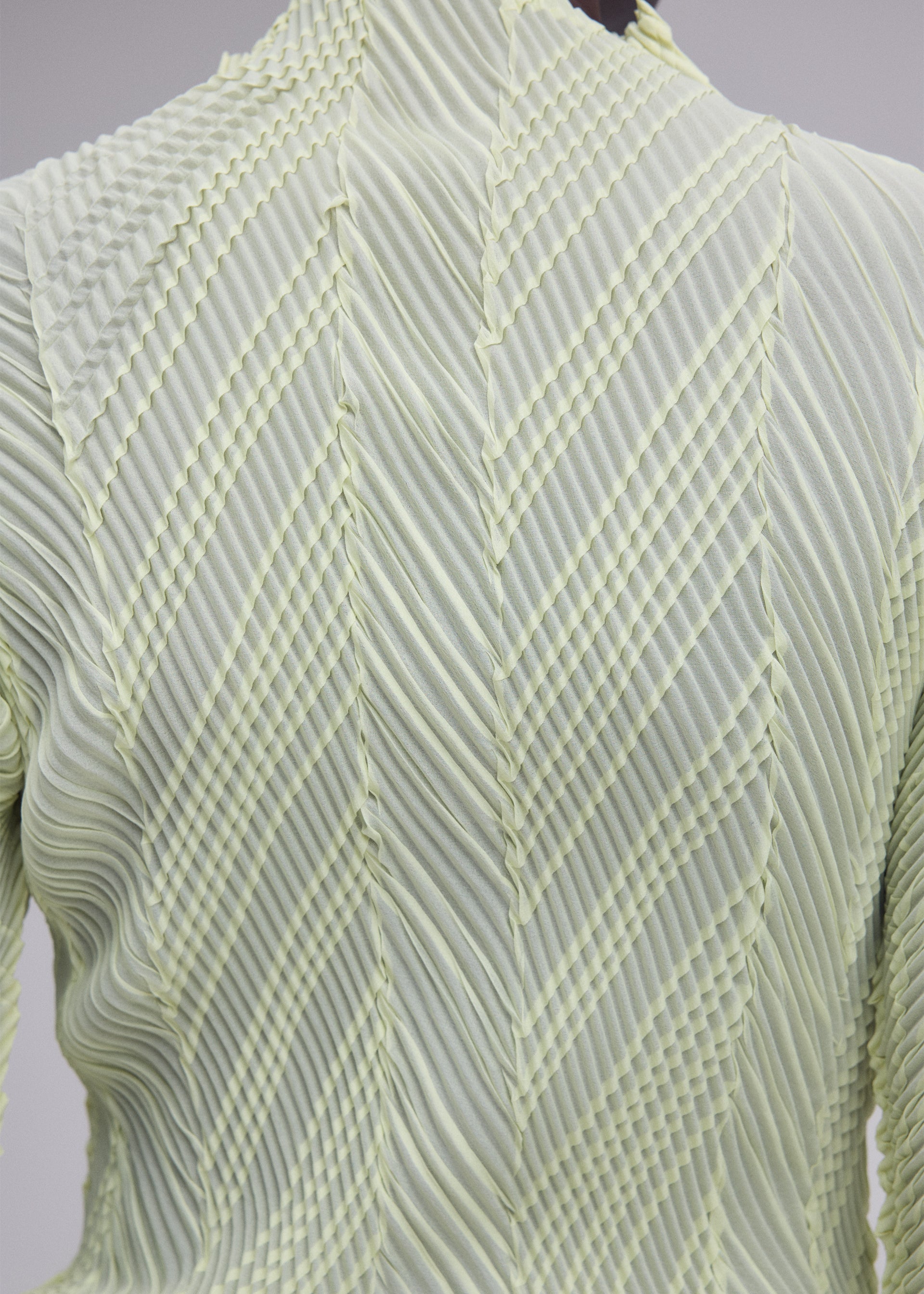 A model wears the ISSEY MIYAKE ZIGZAG PLEATS zigzag-pleats-long-sleeved-top-light-blue.