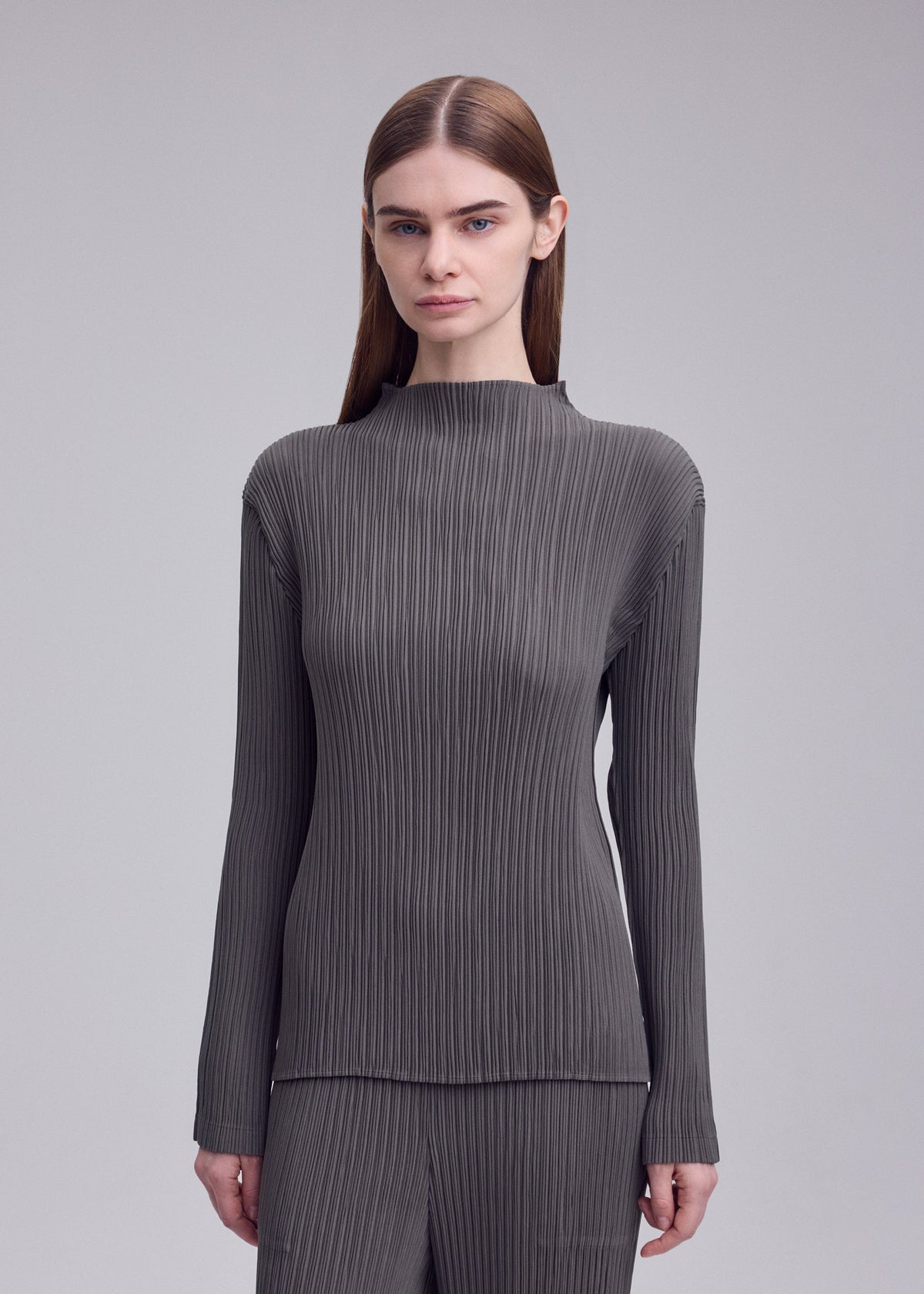 A model wears the ISSEY MIYAKE HATCHING PLEATS hatching-pleats-mock-neckline-top-black.