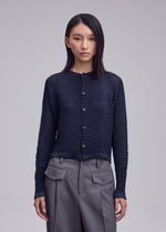 A model wears the ISSEY MIYAKE SUEDE LIKE PLEATS suede-like-pleats-round-neck-cardigan-light-pink.