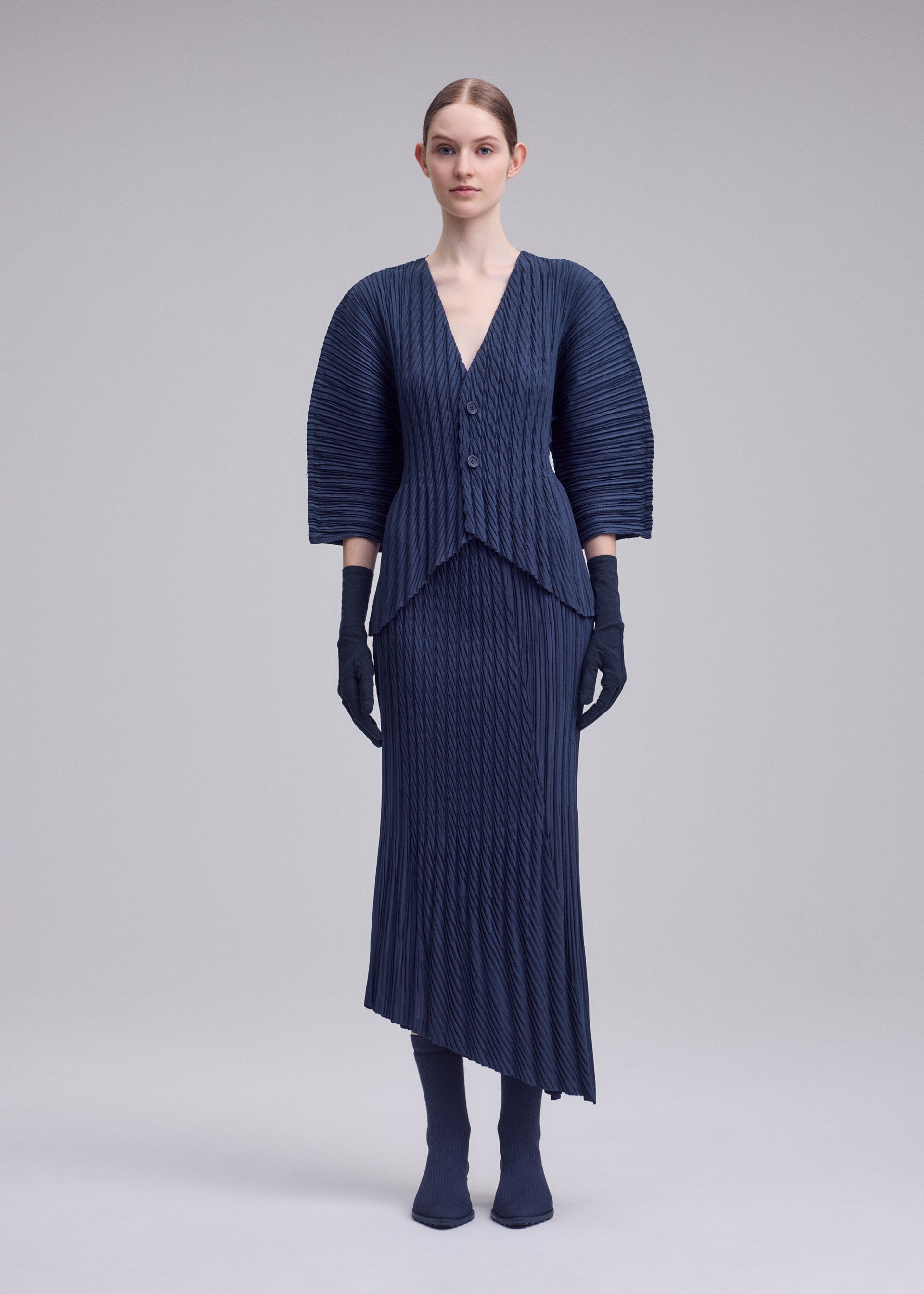 A model wears the ISSEY MIYAKE UNFURLING PLEATS cardigan.