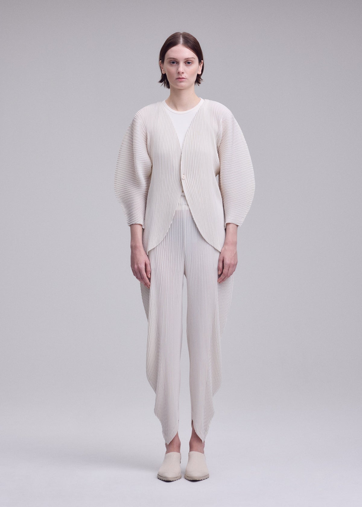 A model wears the ISSEY MIYAKE LEAF PLEATS leaf-pleats-cardigan-dark-navy.
