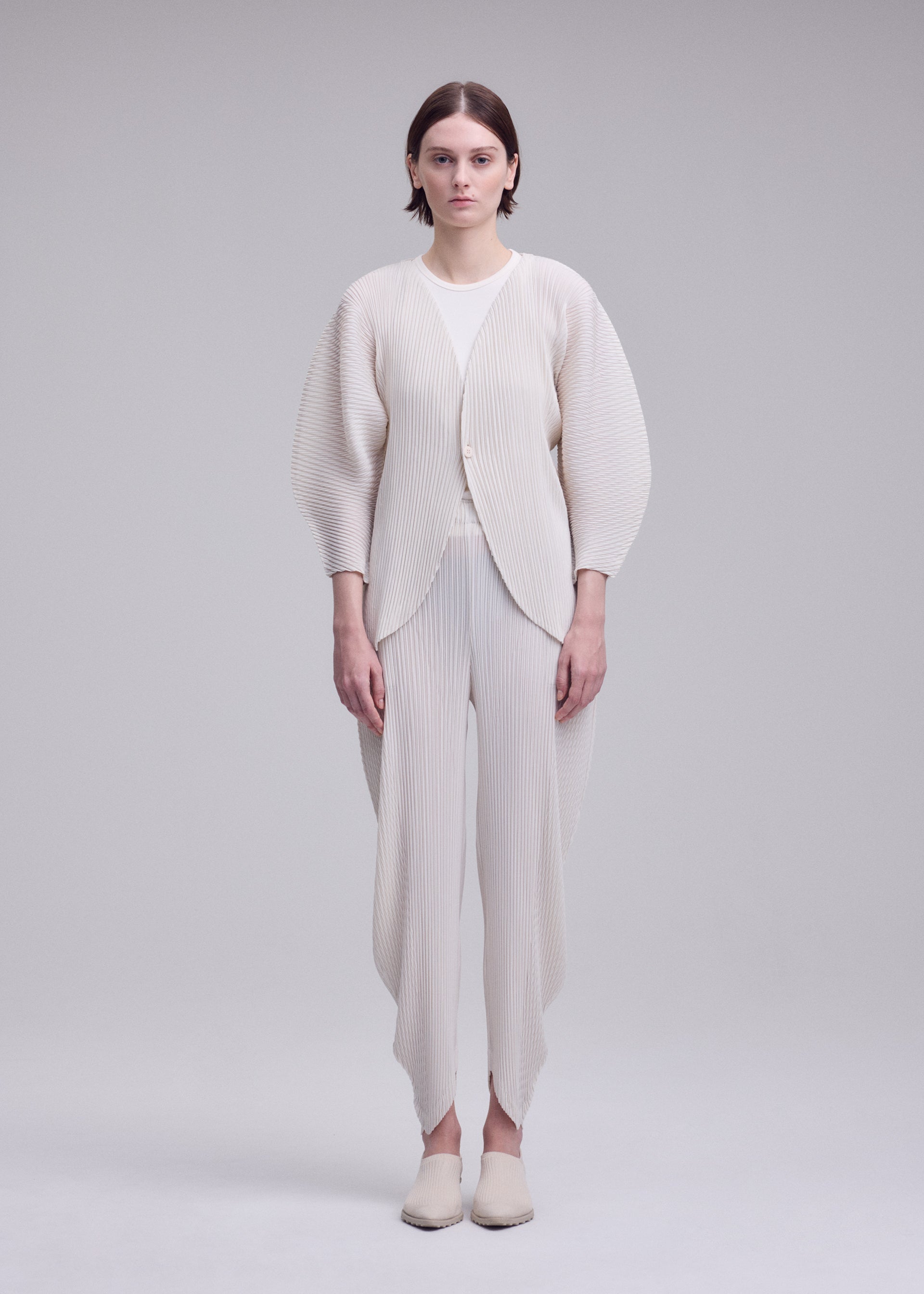 A model wears the ISSEY MIYAKE LEAF PLEATS leaf-pleats-cardigan-dark-navy.