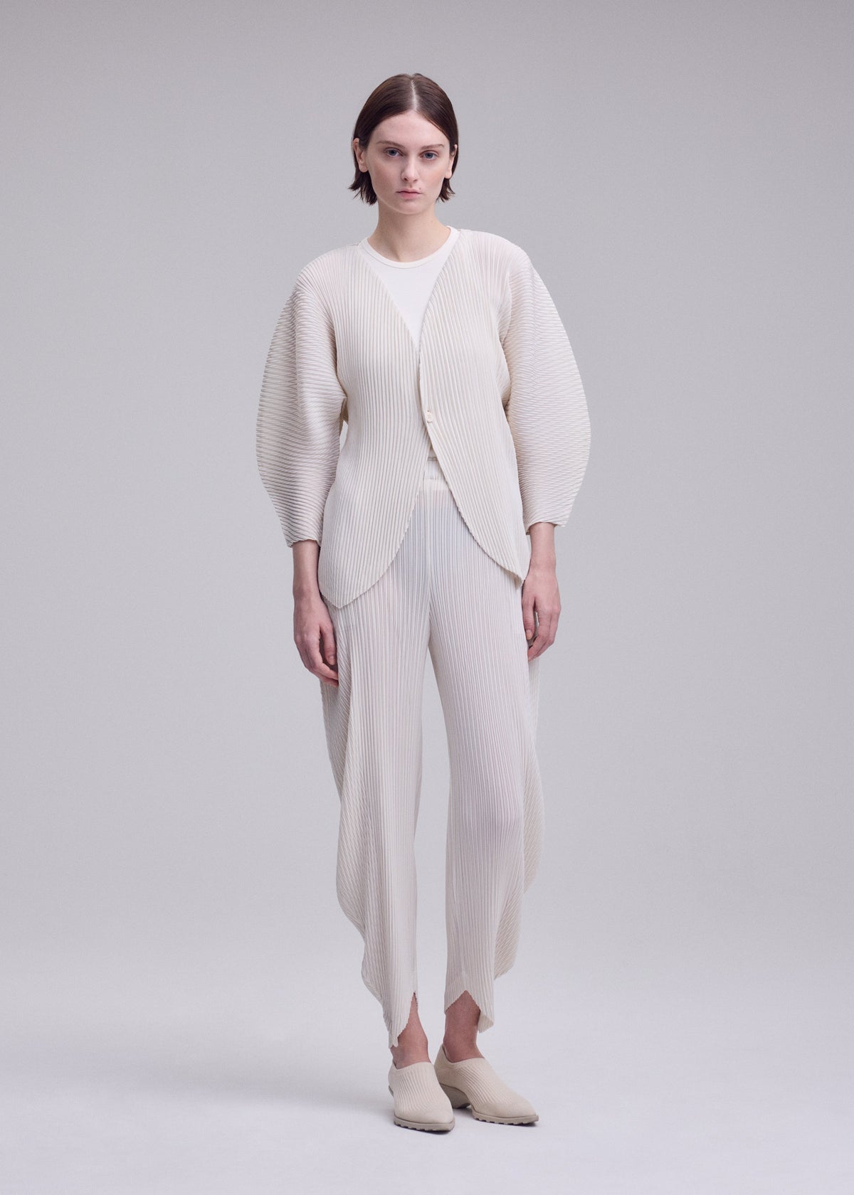 A model wears the ISSEY MIYAKE LEAF PLEATS leaf-pleats-cardigan-dark-navy.