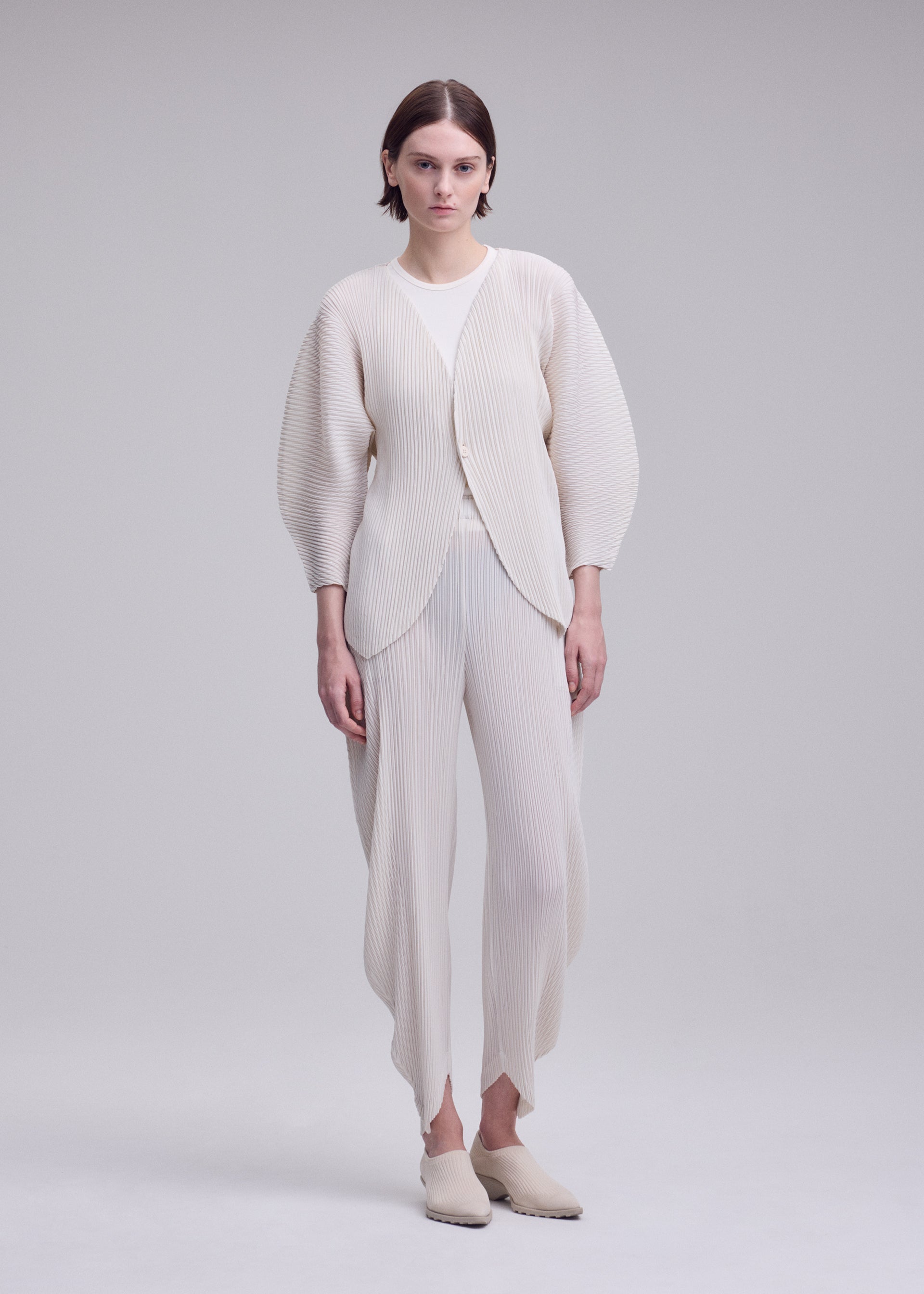 A model wears the ISSEY MIYAKE LEAF PLEATS leaf-pleats-cardigan-dark-navy.