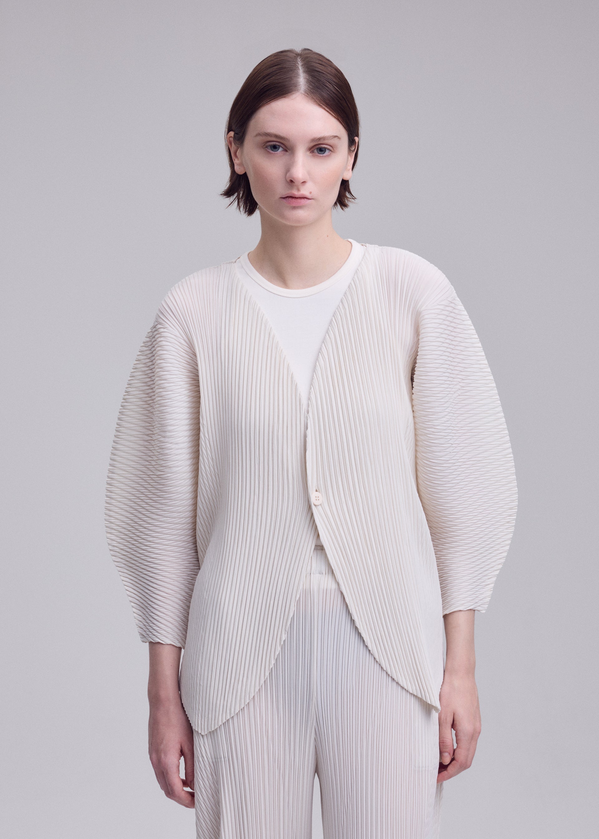 A model wears the ISSEY MIYAKE LEAF PLEATS leaf-pleats-cardigan-dark-navy.