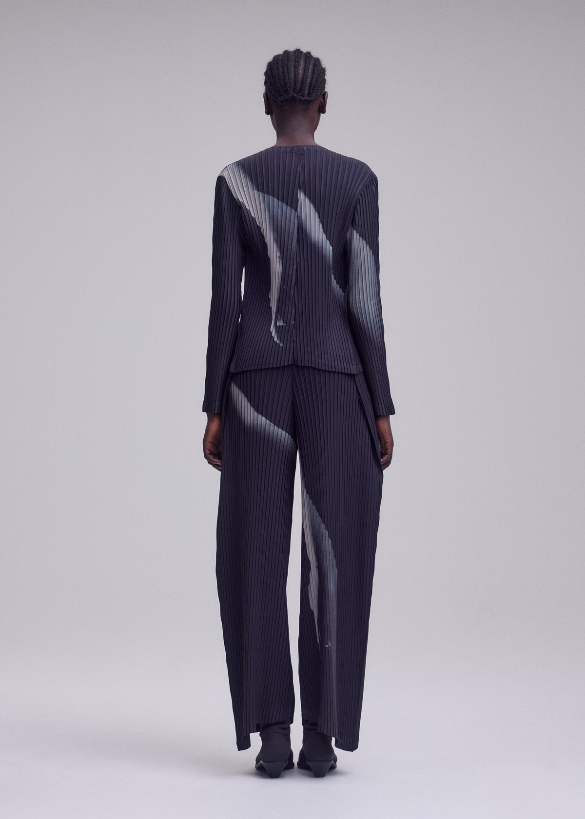 A model wears the ISSEY MIYAKE HANDS OF LOVER PLEATS hands-of-lover-pleats-cardigan-beige-hued.