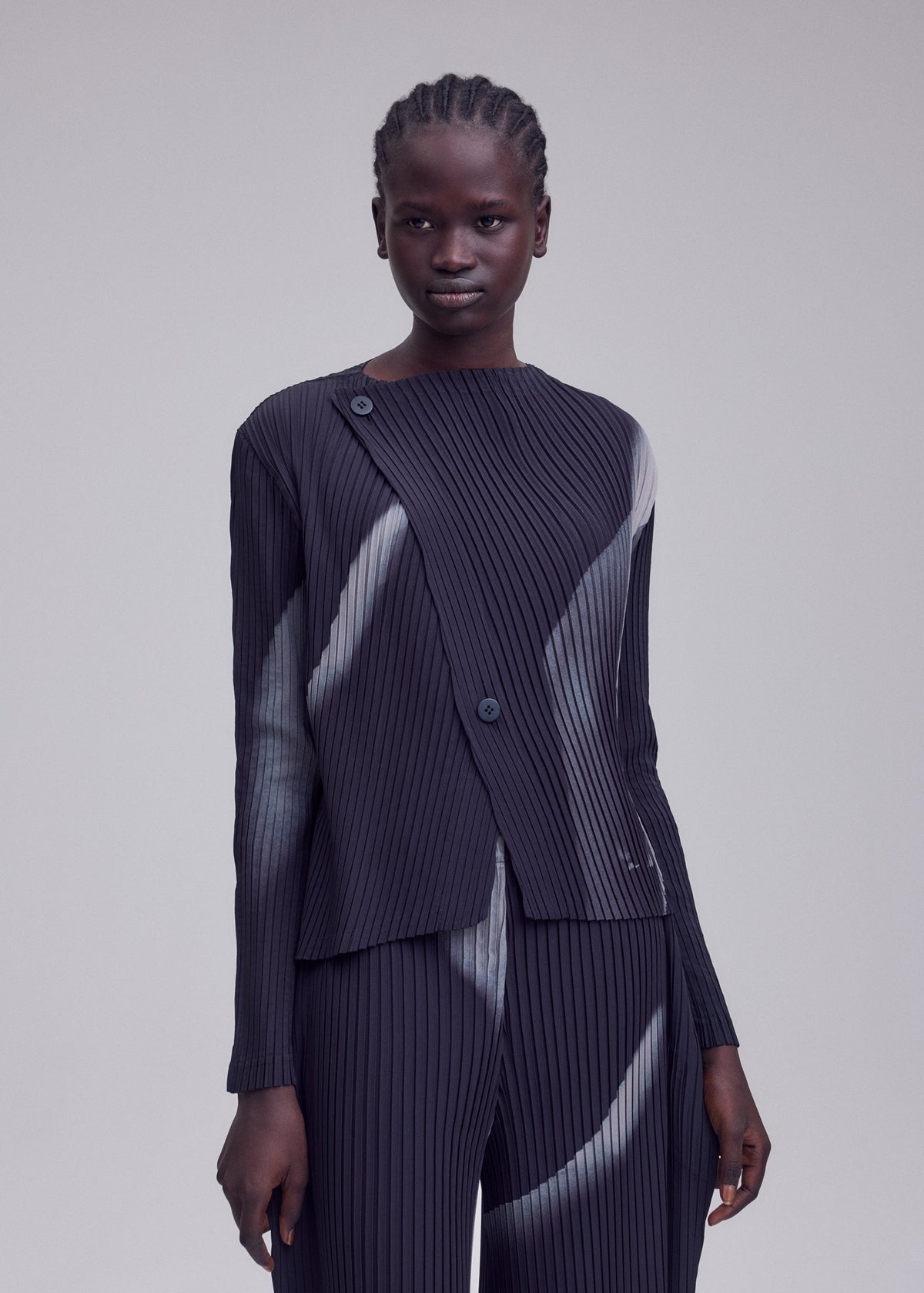 A model wears the ISSEY MIYAKE HANDS OF LOVER PLEATS hands-of-lover-pleats-cardigan-beige-hued.