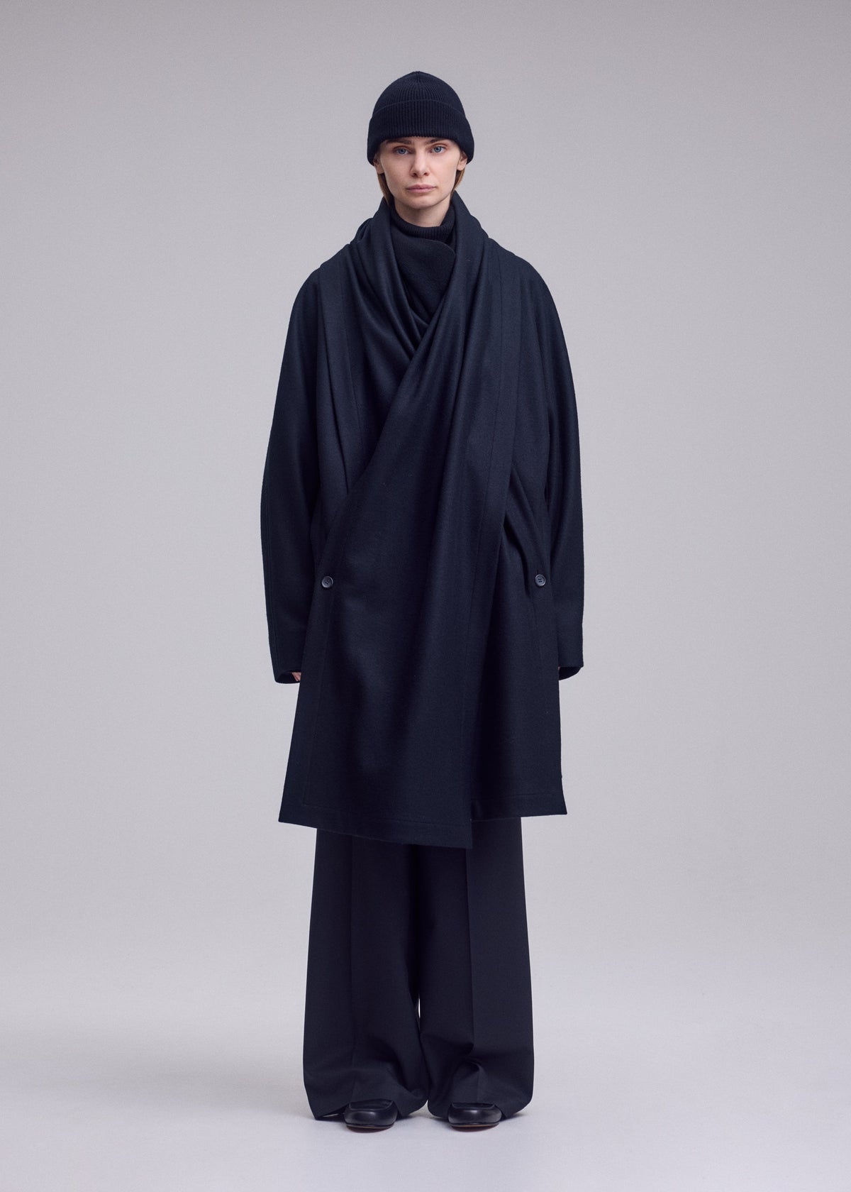 A model wears the ISSEY MIYAKE MANNER manner-coat-black.