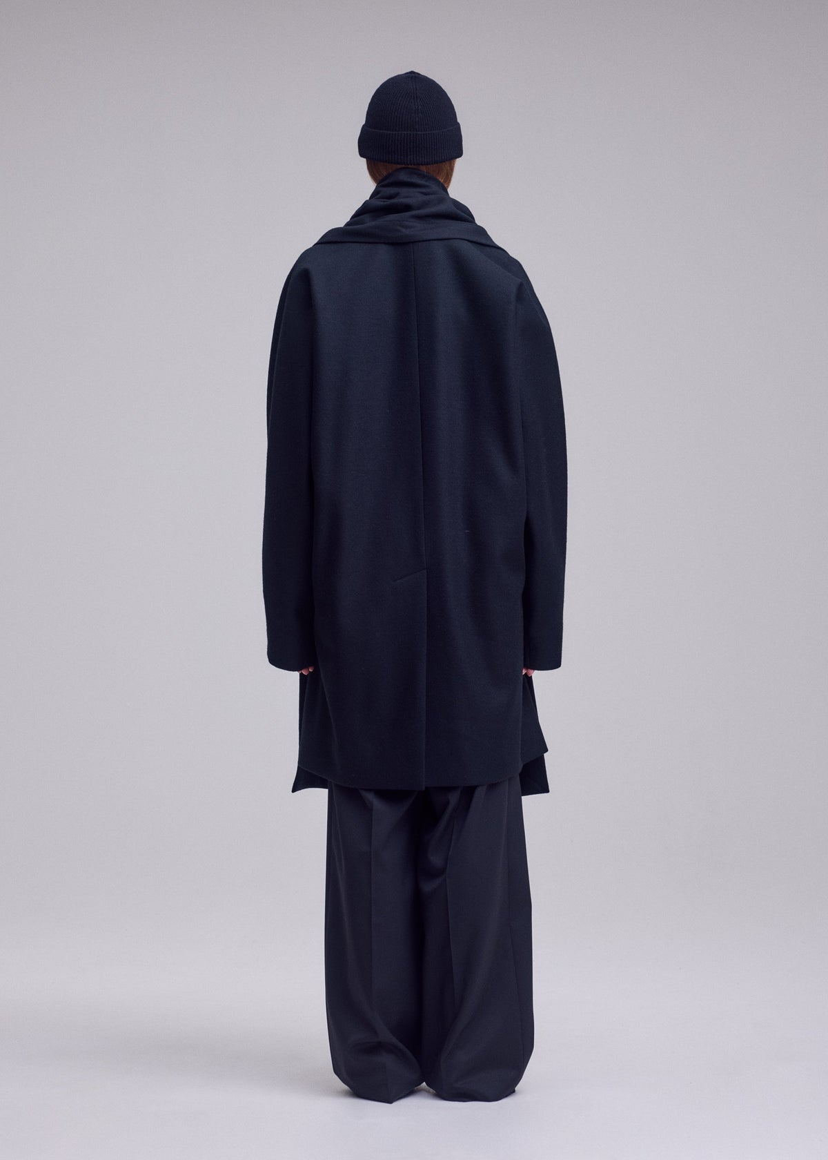 A model wears the ISSEY MIYAKE MANNER manner-coat-black.