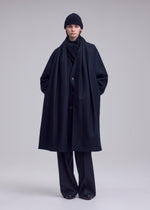 A model wears the ISSEY MIYAKE MANNER manner-coat-black.