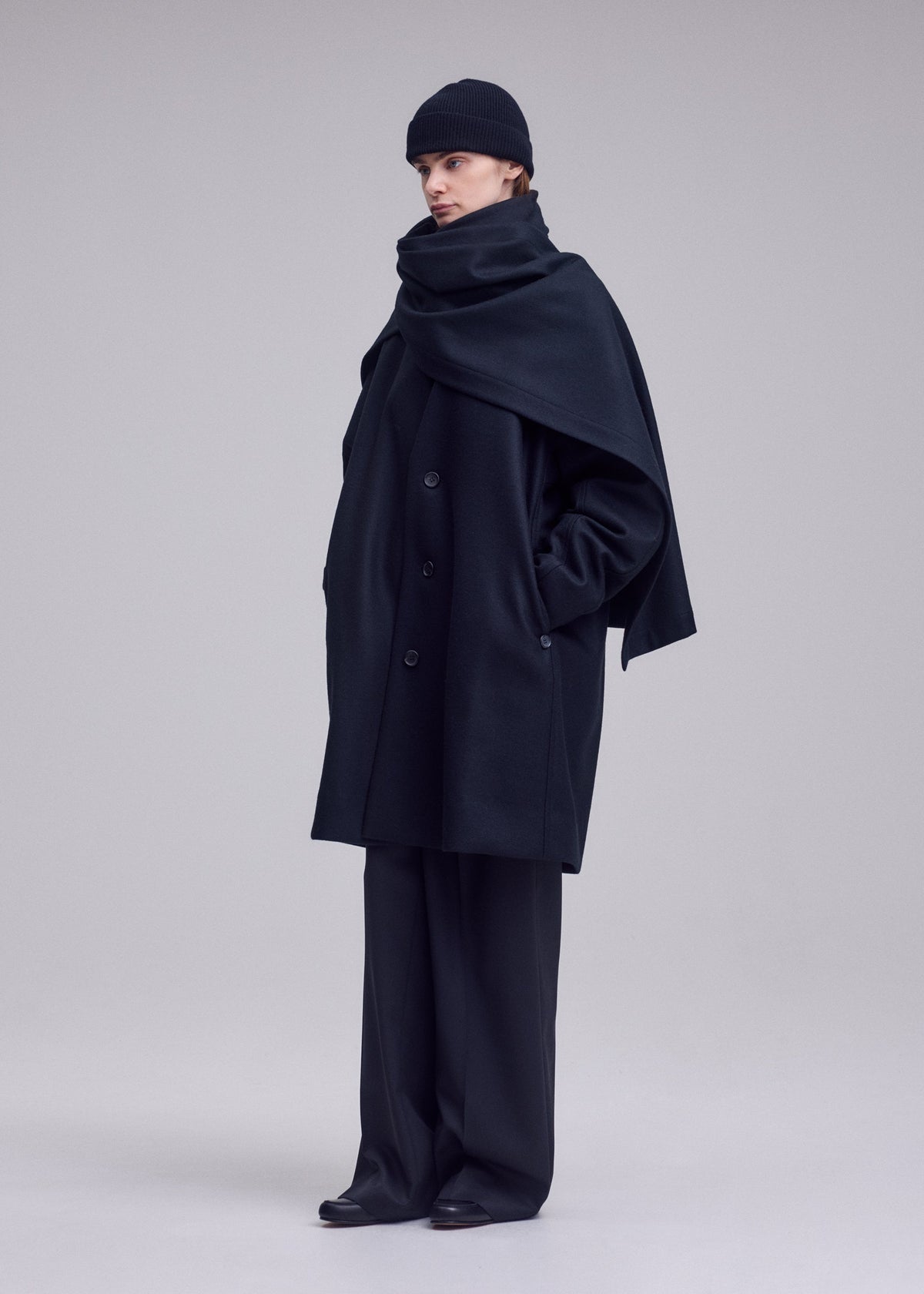 A model wears the ISSEY MIYAKE MANNER manner-coat-black.