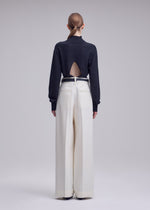 A model wears the ISSEY MIYAKE SHELL shell-trousers-grey.
