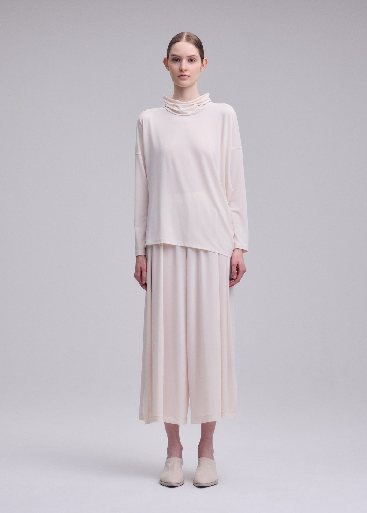 A model wears the ISSEY MIYAKE DRAPE JERSEY-68 shirt.