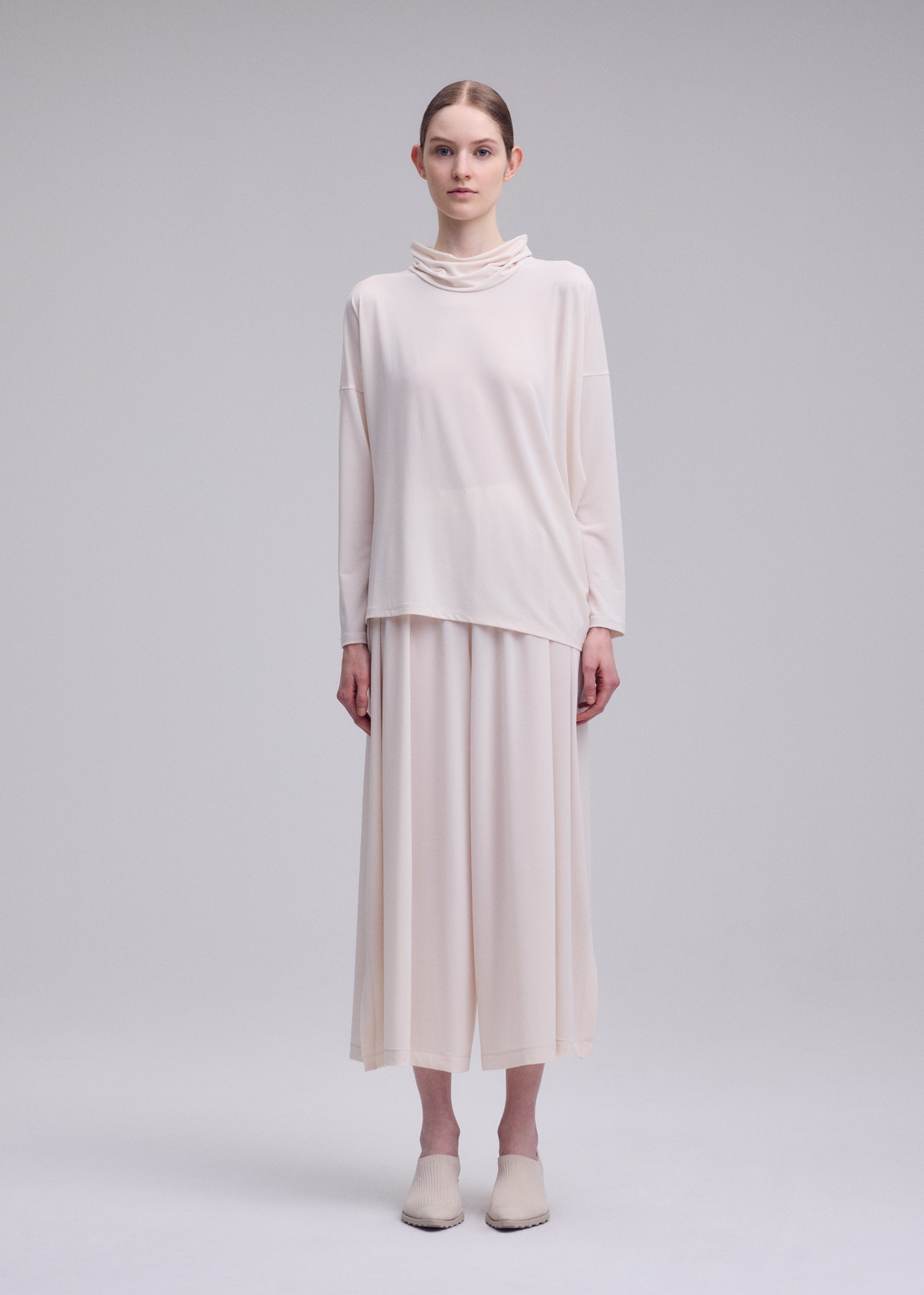 A model wears the ISSEY MIYAKE DRAPE JERSEY-68 shirt.