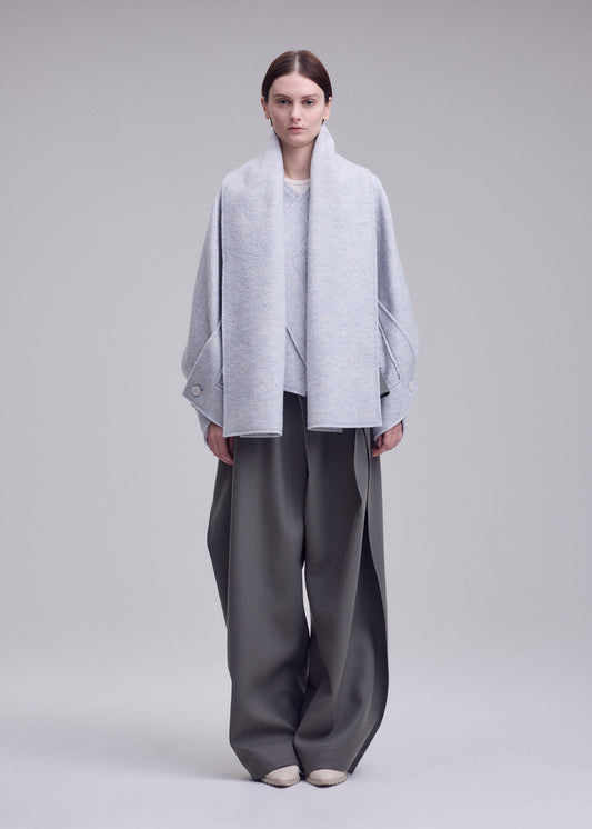 A model wears the ISSEY MIYAKE WOOLEN GRANITE woolen-granite-coat-beige.