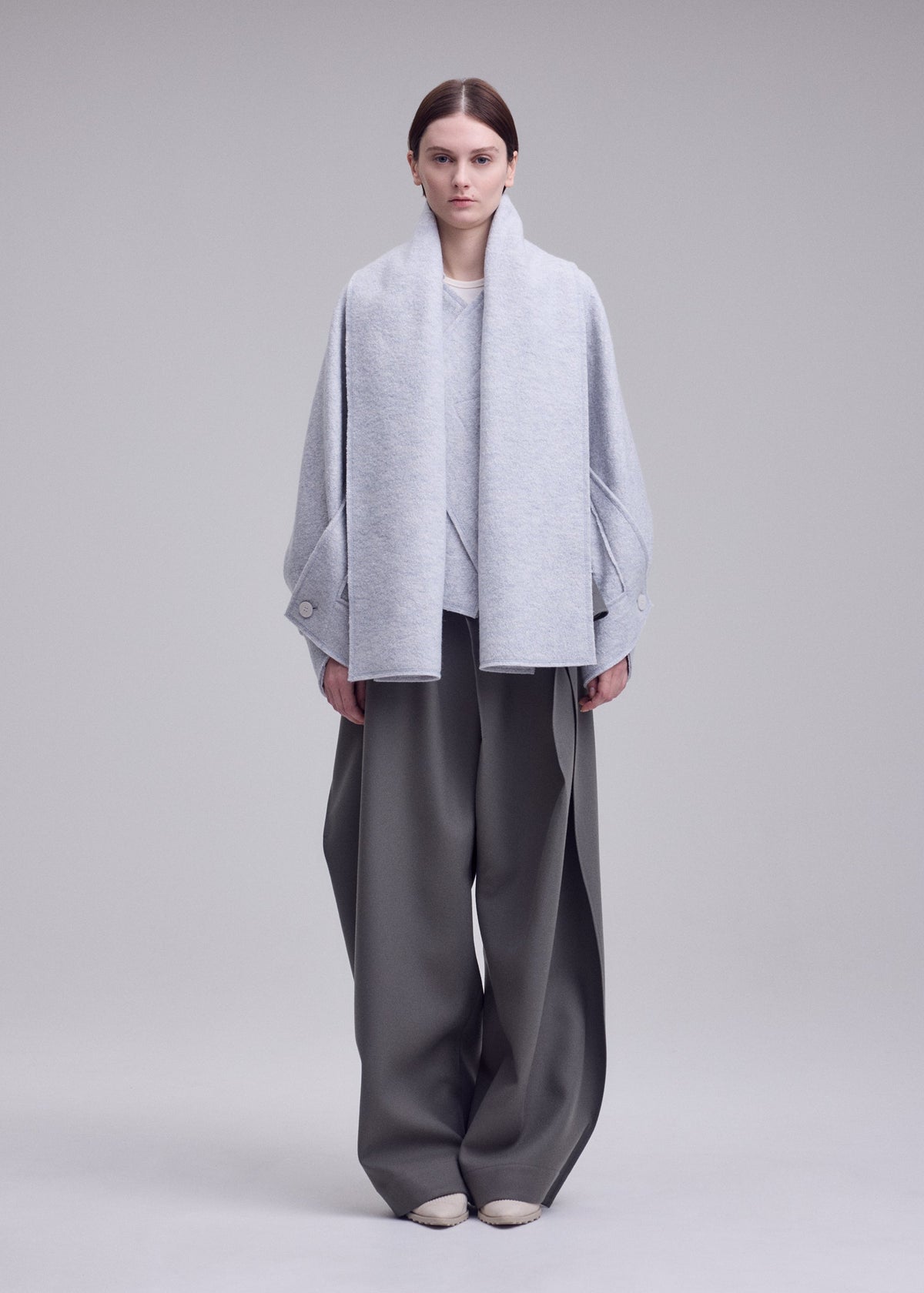 A model wears the ISSEY MIYAKE WOOLEN GRANITE woolen-granite-coat-black.