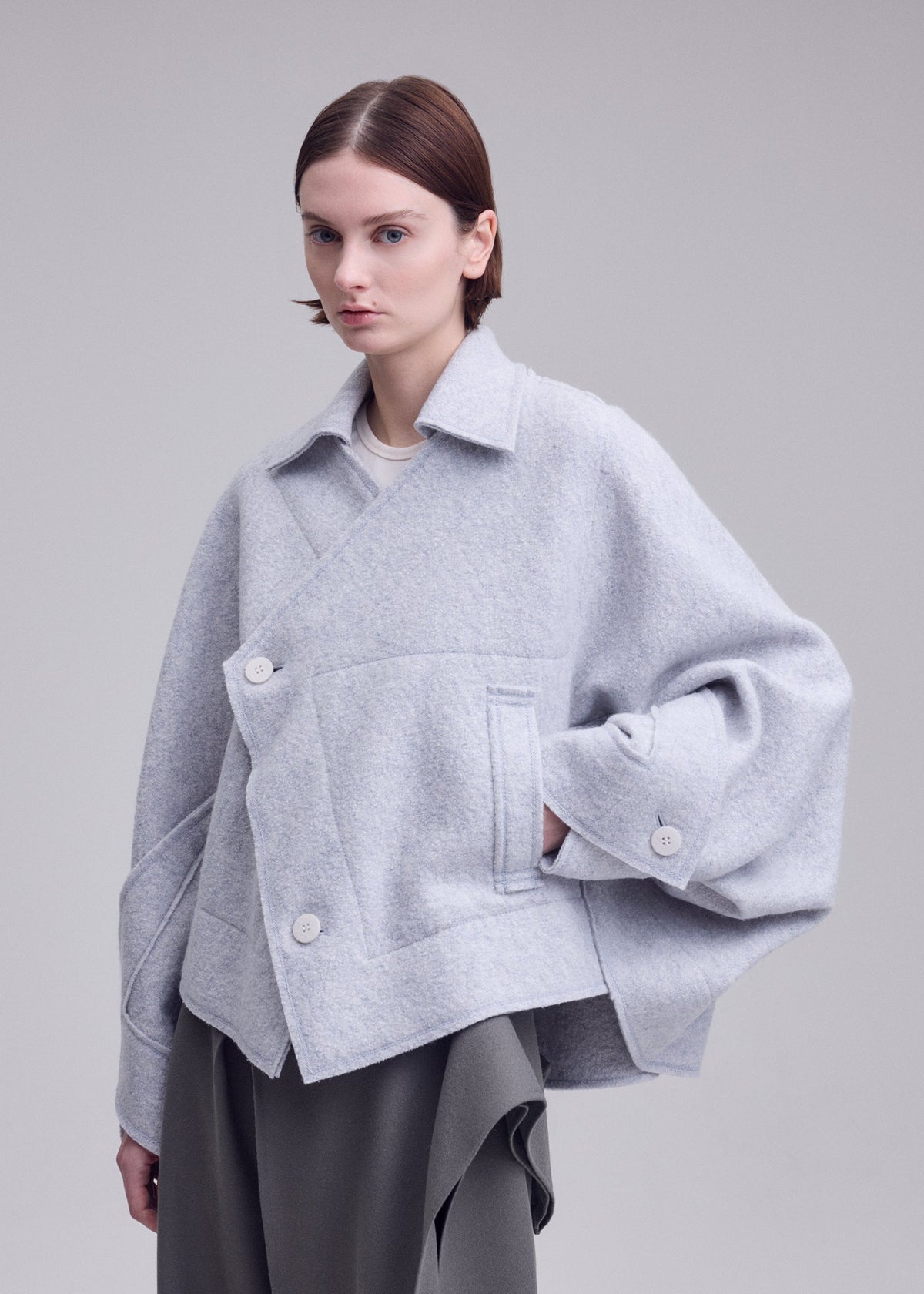 A model wears the ISSEY MIYAKE WOOLEN GRANITE woolen-granite-coat-black.