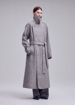 A model wears the ISSEY MIYAKE WOOLEN GRANITE woolen-granite-coat-beige-1.