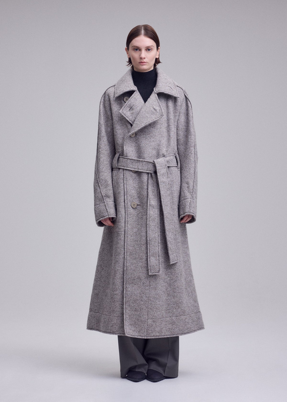 A model wears the ISSEY MIYAKE WOOLEN GRANITE woolen-granite-coat-beige-1.