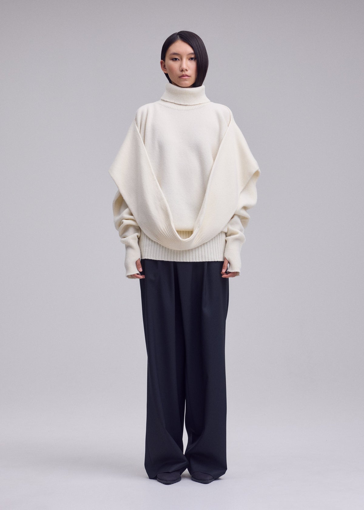 A model wears the ISSEY MIYAKE O KNIT o-knit-high-neck-top-black.