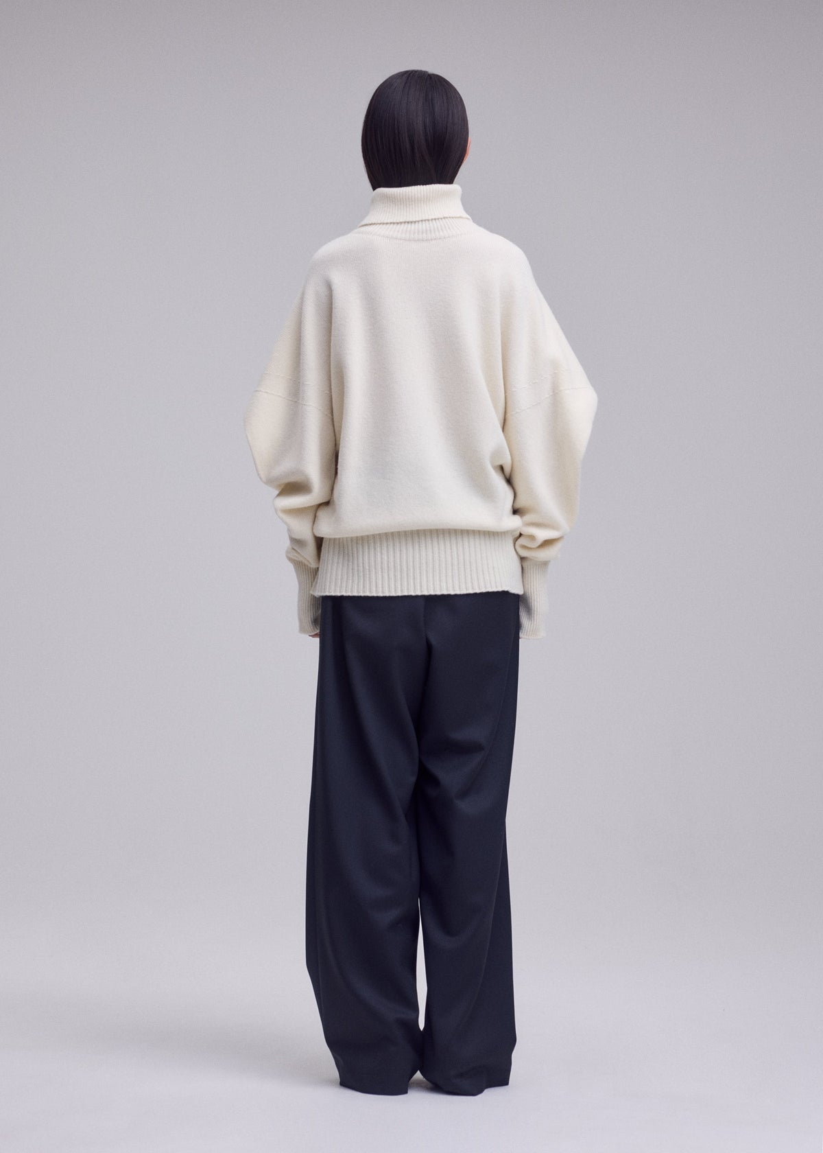 A model wears the ISSEY MIYAKE O KNIT o-knit-high-neck-top-off-white.