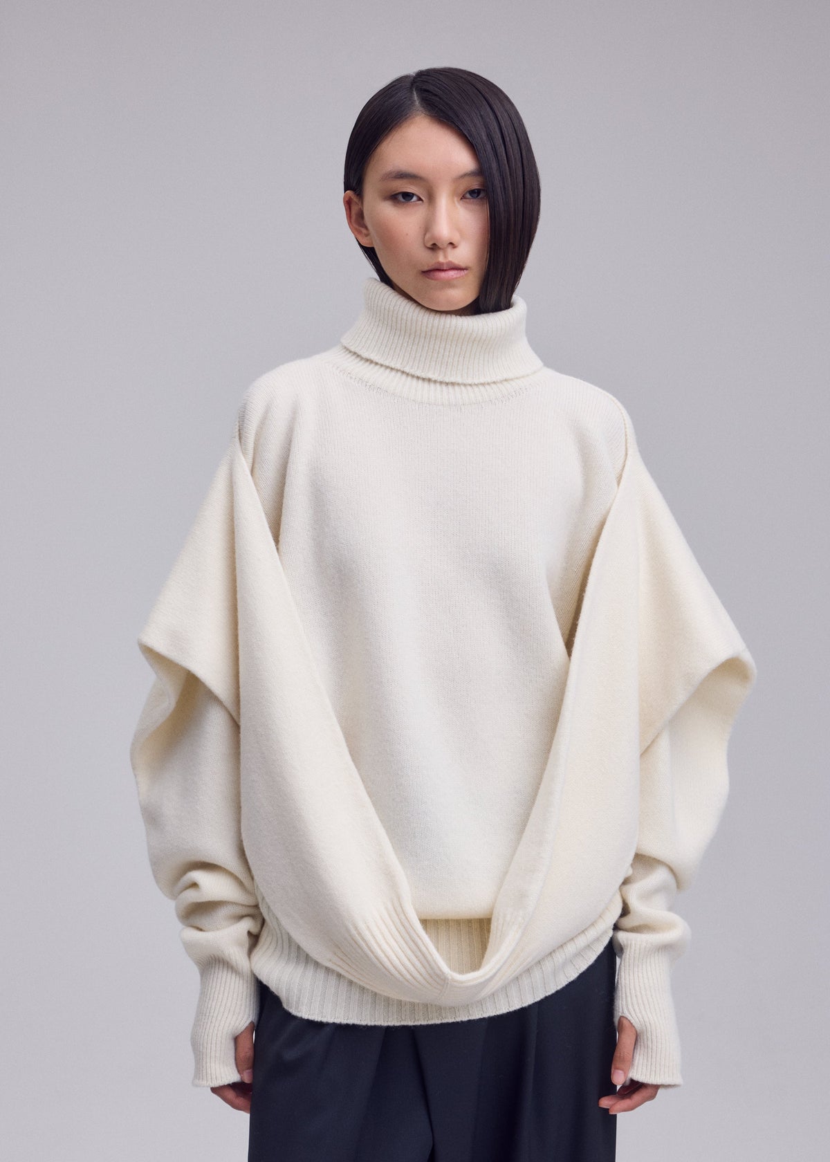 A model wears the ISSEY MIYAKE O KNIT o-knit-high-neck-top-off-white.
