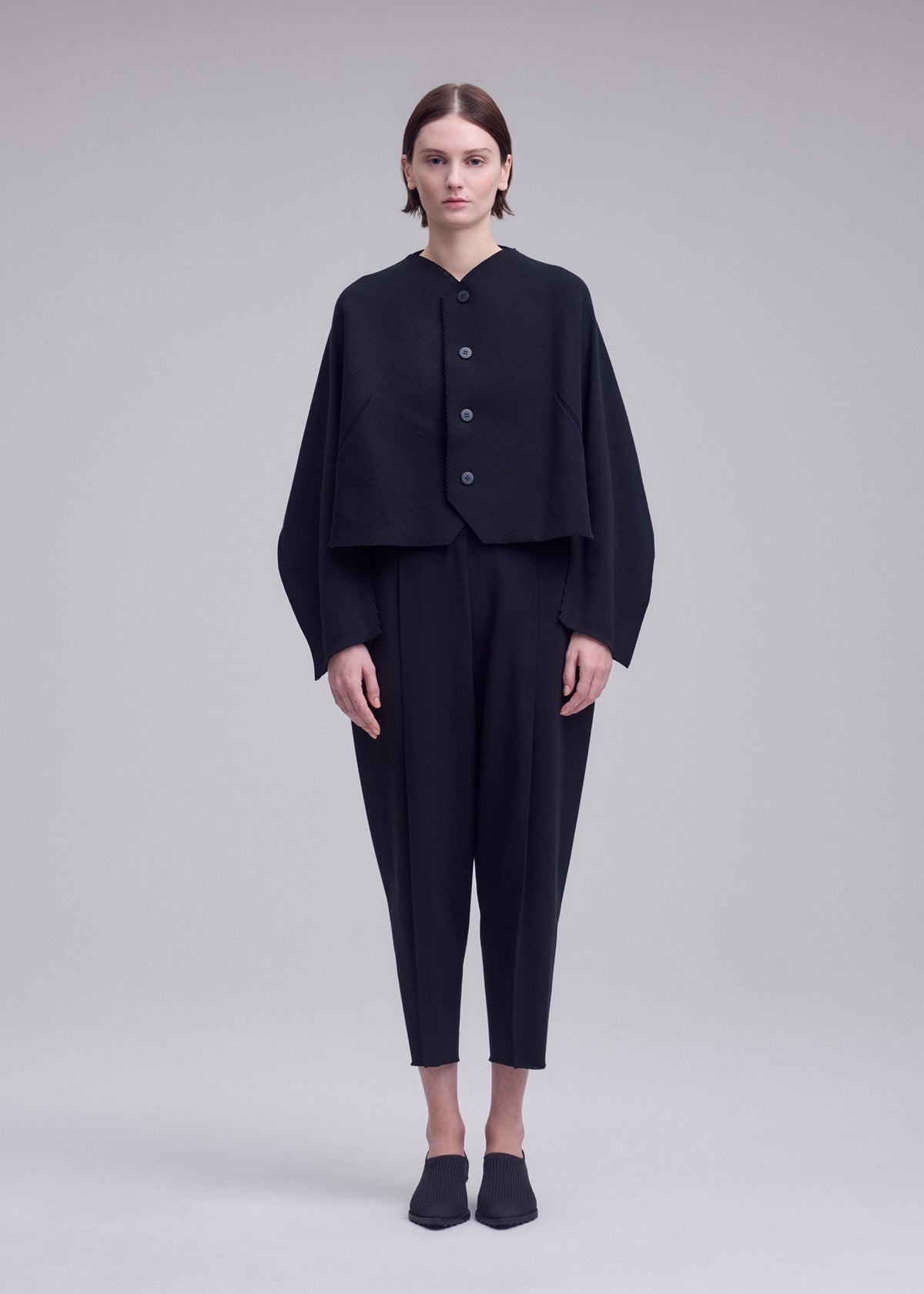 A model wears the ISSEY MIYAKE CAMPAGNE campagne-button-front-cardigan-dark-navy.