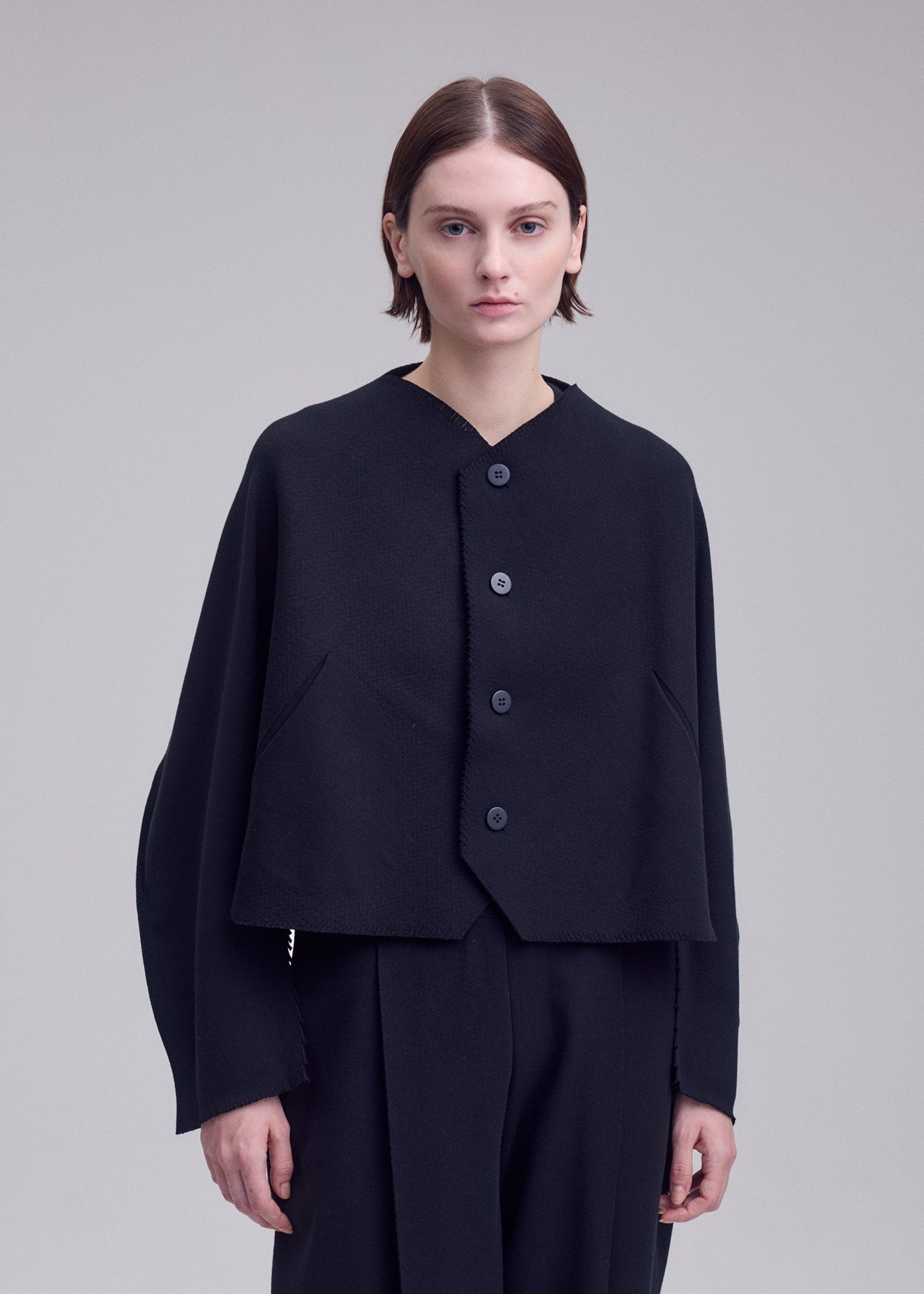 A model wears the ISSEY MIYAKE CAMPAGNE campagne-button-front-cardigan-dark-navy.