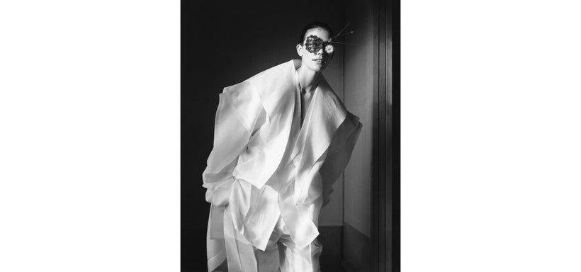 Centre: Model wearing PRESS AND PRESSED Coat, Jacket and trousers in Washi White, accessorised with a floral glasses piece. Hands in pockets, relaxed pose. Black and white image.