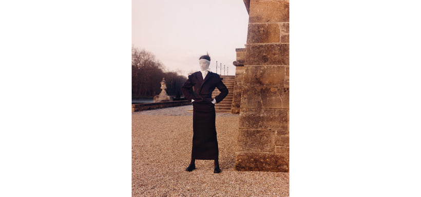 Centre: Model wearing LIKE TORSO LIKE BLAZER Dress in Dark Brown, striking a confident pose in front of a brick building with a fountain in the background.