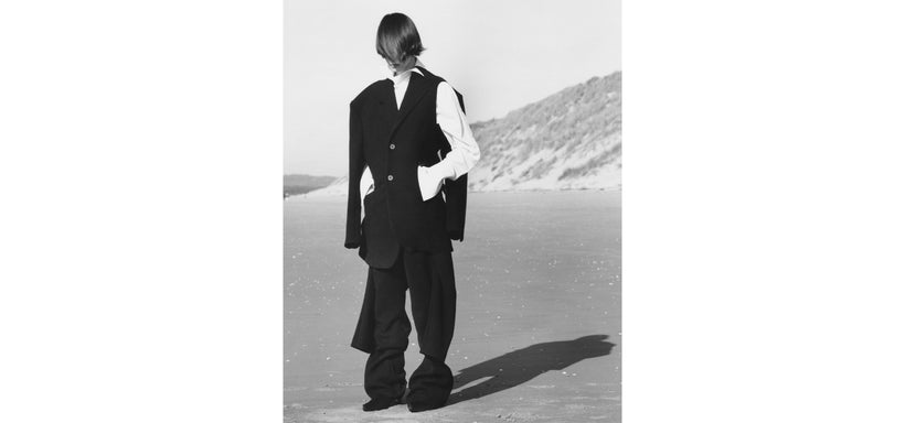 Centre: Model wearing ARMS Jacket and Trousers in Black, standing on a sandy surface with a desert landscape in the background.