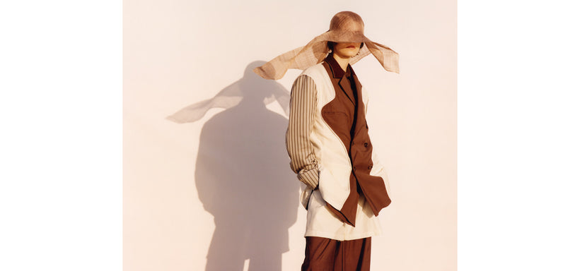 Centre: Model wearing PALINDROME Jacket and Trousers in Dark Brown, relaxed pose against a light pink background.
