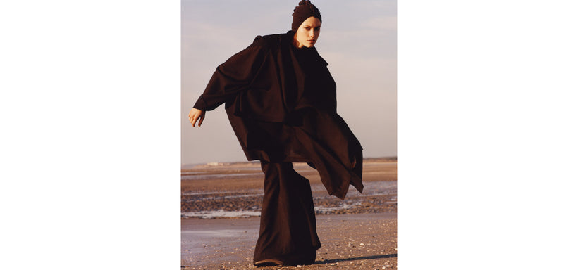 Centre: Model wearing ALL SQUARES Top and Trousers in Burgundy, in an expressive pose against a seascape background.