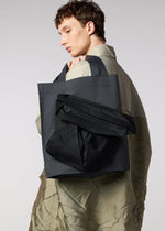 A model wears the IM MEN MONOLITH bag.