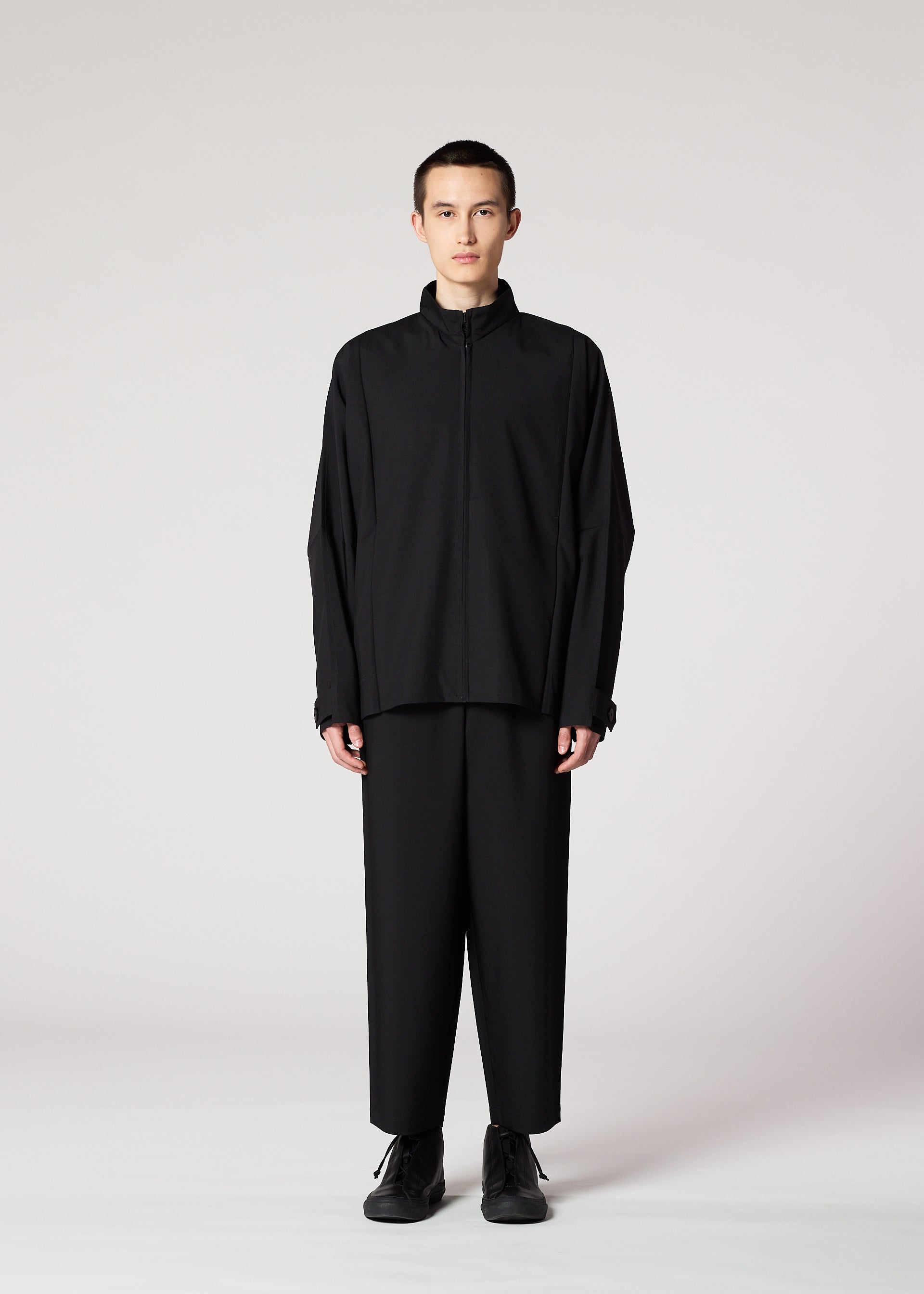 A model wears the IM MEN FLAT BLACK trousers.