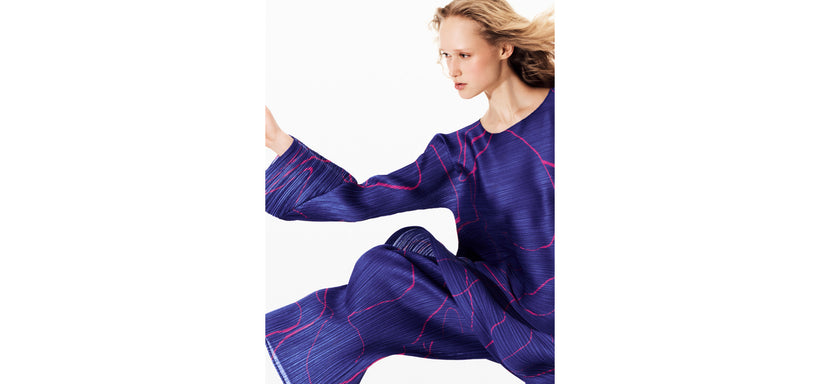 Centre: Model wearing PAUSE tunic and trousers in Blue in a dynamic pose against a white background.