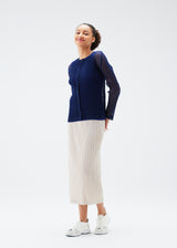 A model wears the PLEATS PLEASE ISSEY MIYAKE  TATAMI JULY cardigan