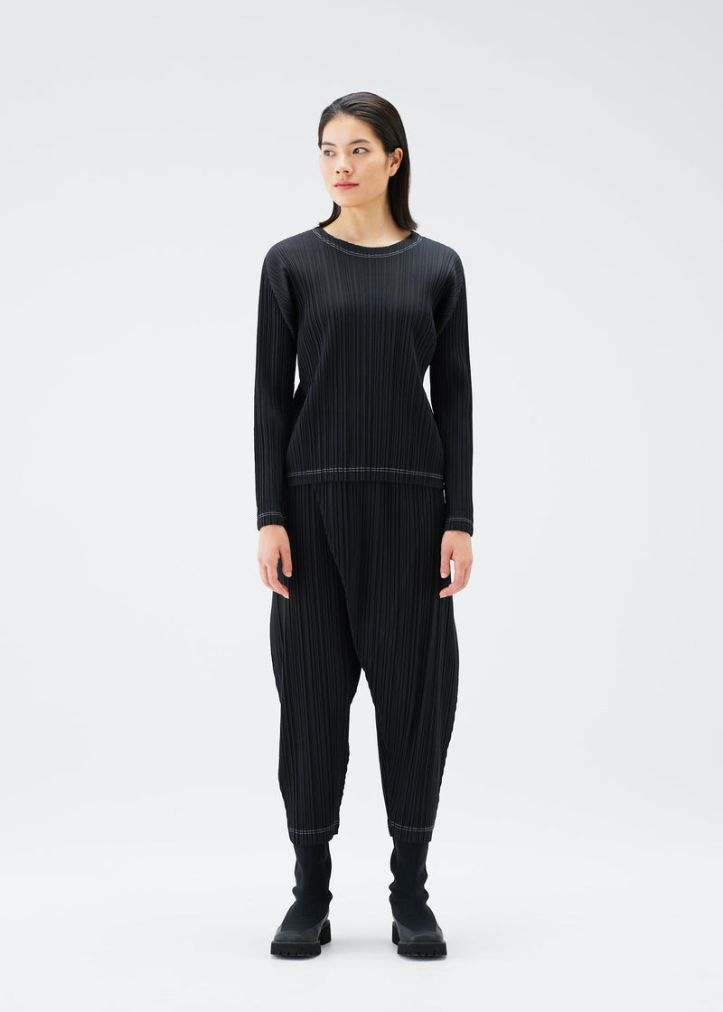 A model wears the PLEATS PLEASE ISSEY MIYAKE RAMIE PLEATS trousers.