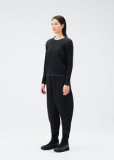 A model wears the PLEATS PLEASE ISSEY MIYAKE RAMIE PLEATS trousers.